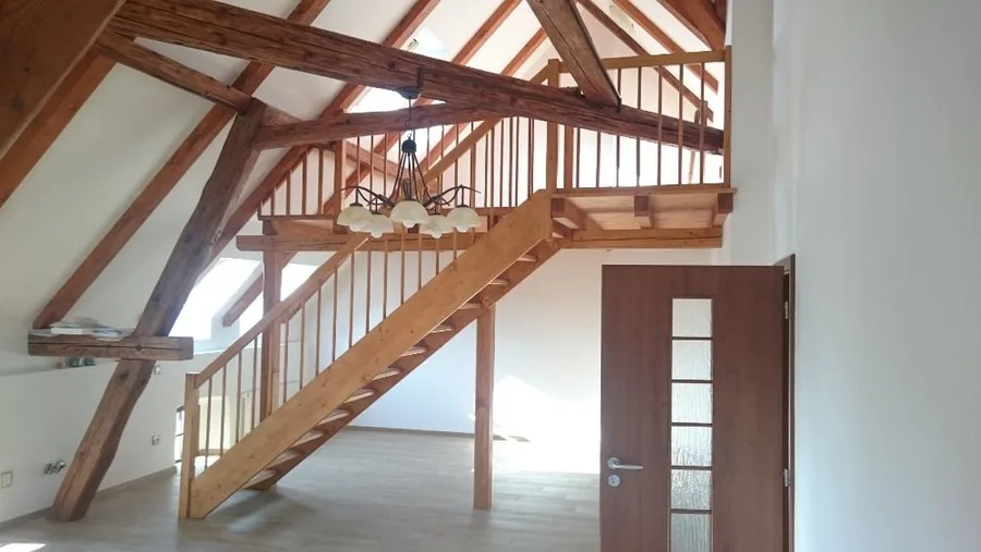 Dřevěné schodiště v&nbsp;interiéru pod přiznanými krokvemi