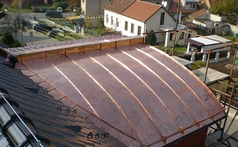 Falcovaná červenohnědá plechová střecha nízkého sklonu, pohled přes hřeben